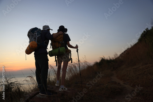 A couple of backpackers  trekking during sunset over the horizon photo