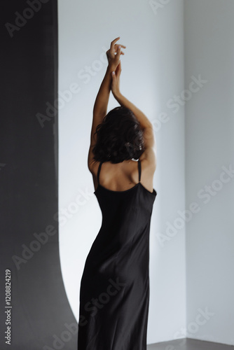 Obraz na płótnie Beautiful brunette woman posing in black dress on black background