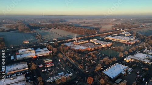 Frozen rooftops of company and factory during golden sunrise in industrial area. Traffic on highway and snowy farm fields in distance. Aerial wide shot. photo