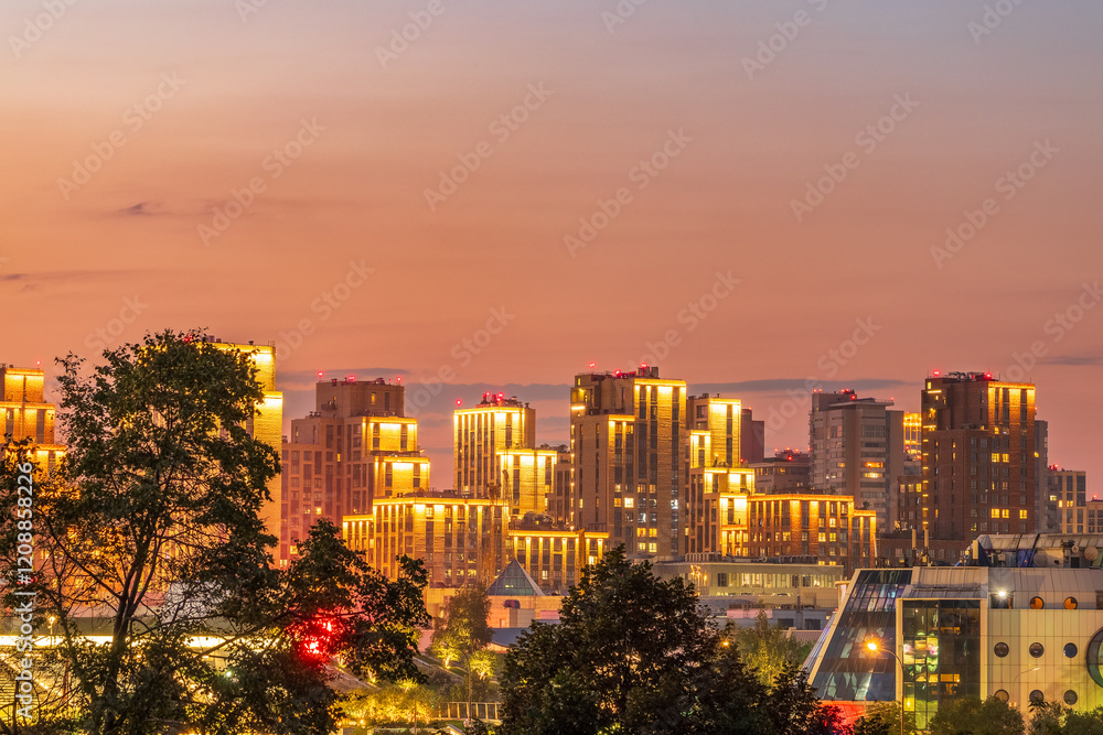 Fototapeta premium Multi-storey buildings at night with illumination. Night colorful windows lights of the high-rise residential building in city sleeping area