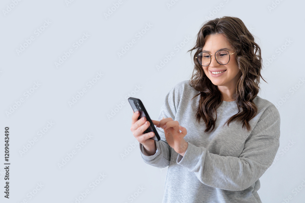Beautiful European woman in gray knitted suit smiles and writes a message in messenger on smartphone Beautiful European woman in gray knitted suit smiles and writes a message in messenger on smartphone