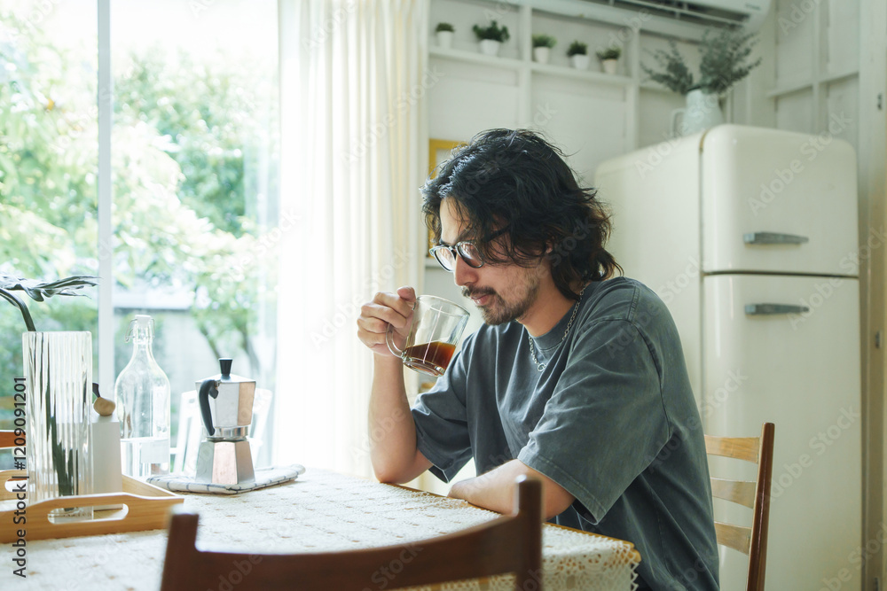 Japanese man relaxing with a cup of coffee at home, sitting by the table in a bright kitchen, enjoying a peaceful holiday morning. Japanese man relaxing with a cup of coffee at home, sitting by the table in a bright kitchen, enjoying a peaceful holiday morning.