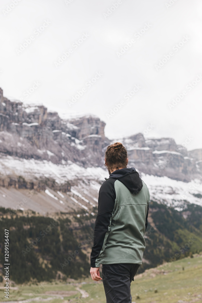 Hiker, with his back to the camera, admires the snow-capped mountains of the Aragonese Pyrenees on the famous Cola de caballo route. Hiker, with his back to the camera, admires the snow-capped mountains of the Aragonese Pyrenees on the famous Cola de caballo route.