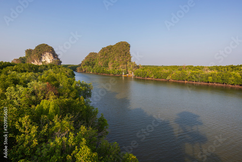Khao Kanab Nam, the two famous twin limestone mountains, and mangrove forests by the Krabi River in Krabi Town, Thailand, viewed from above on a sunny day.