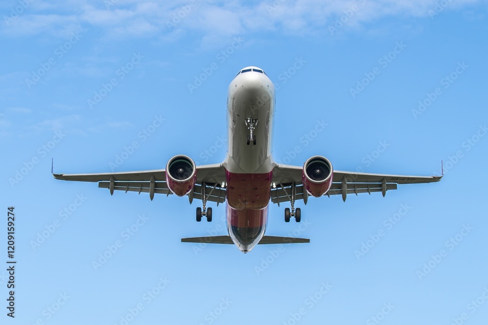 Airplane flying overhead against a clear blue sky near the airport during the day