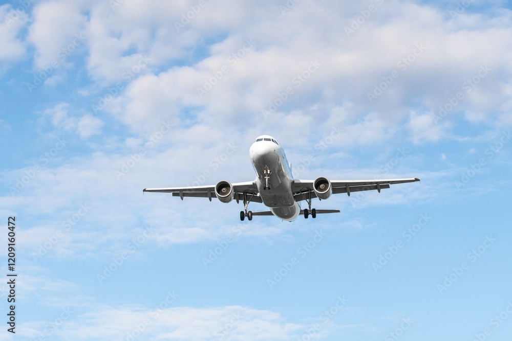 Airplane approaches landing at the airport under a partly cloudy sky in a serene atmosphere during daylight Airplane approaches landing at the airport under a partly cloudy sky in a serene atmosphere during daylight