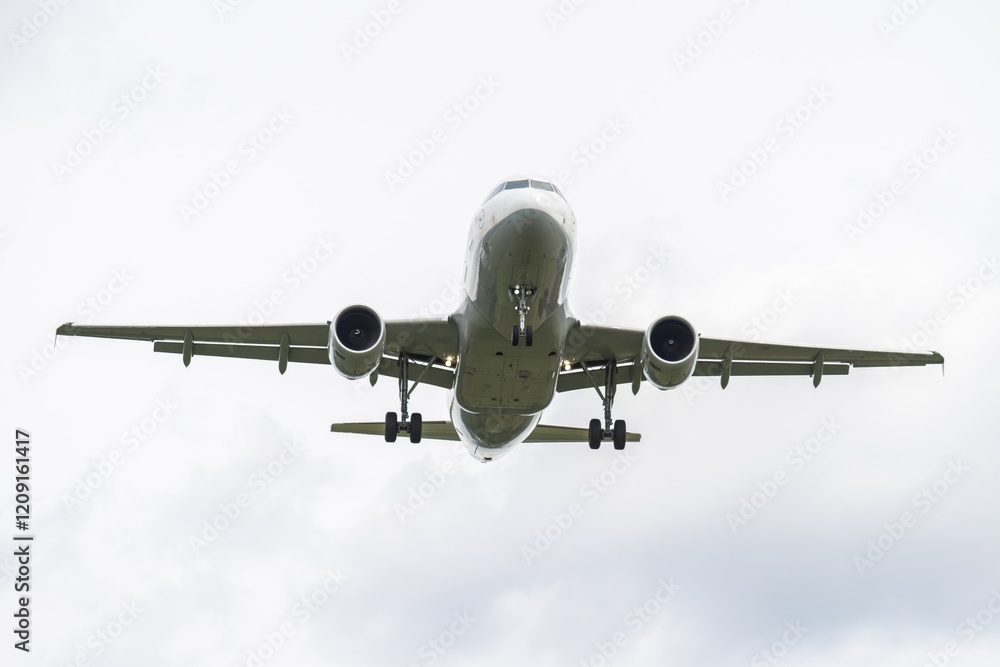 Airplane approaches landing at an airport against a cloudy sky in an urban environment. Airplane approaches landing at an airport against a cloudy sky in an urban environment.