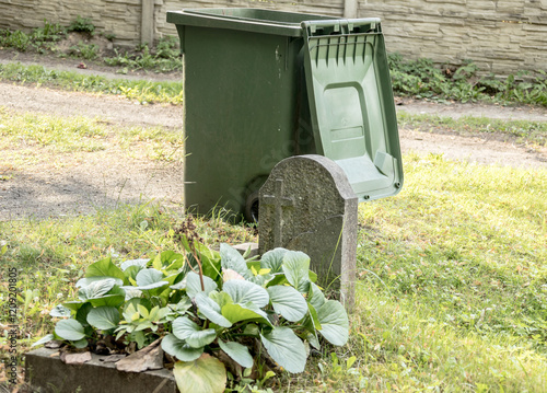 Canvas Print a garbage can standing next to a neglected grave, cemetery, tombstone, garbage c