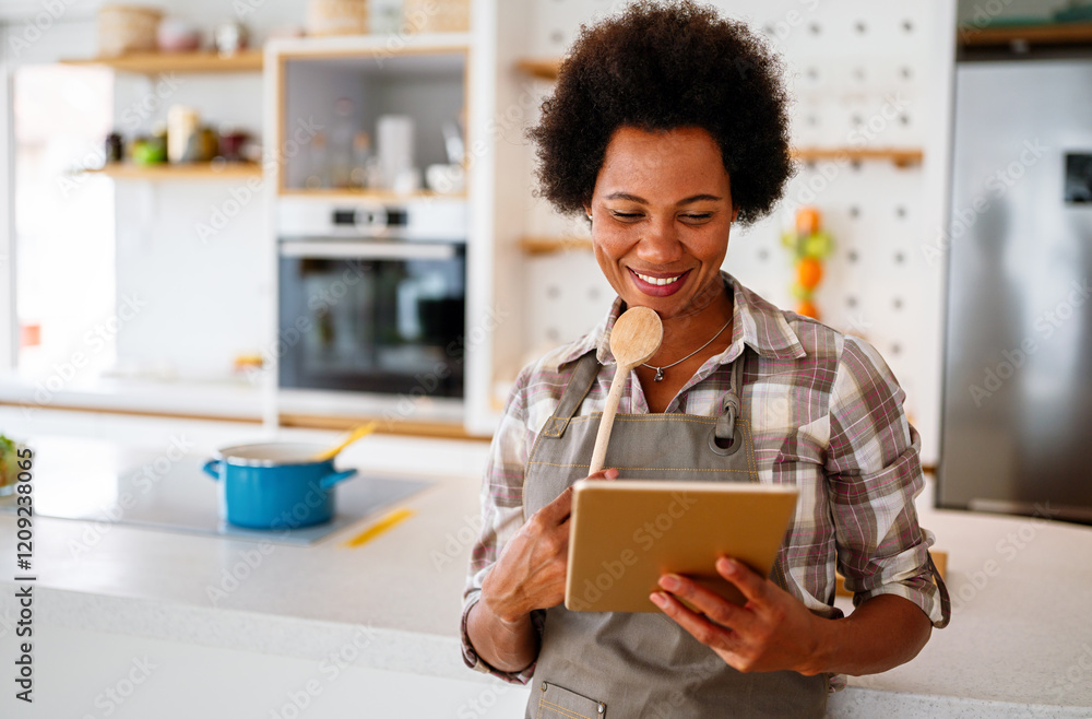 Young african american woman using a tablet computer to cook in her kitchen Young african american woman using a tablet computer to cook in her kitchen