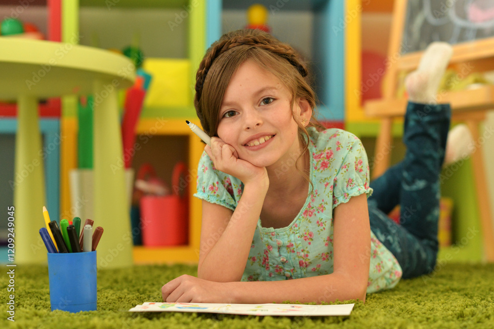 girl in the nursery draws lying on the carpet. girl in the nursery draws lying on the carpet.