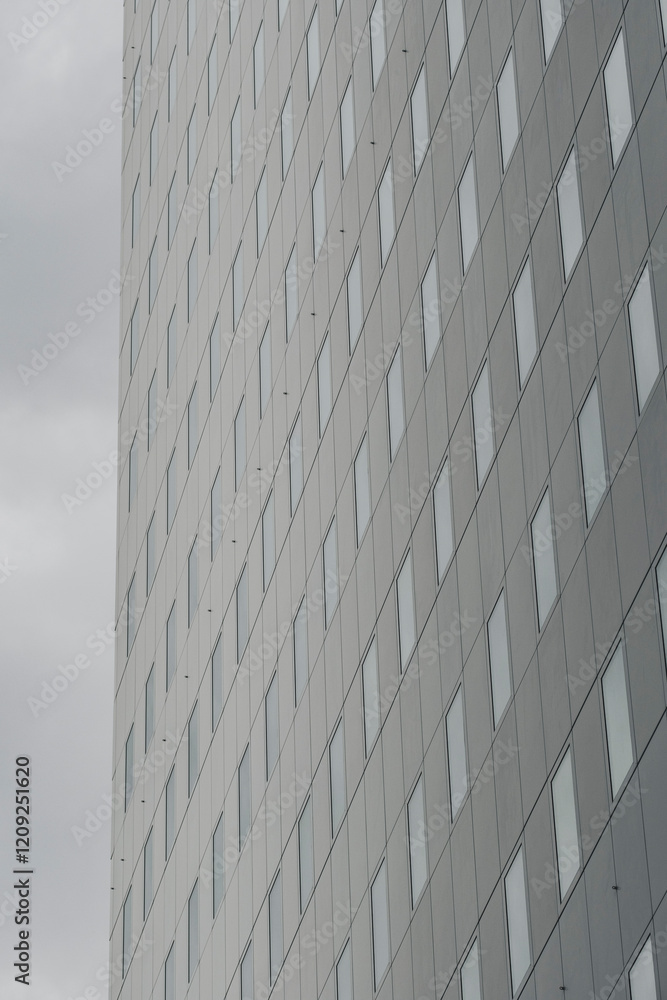 A vertical image of a modern office building characterized by its grid of glass windows, emphasizing the clean lines and contemporary design prevalent in urban architecture. A vertical image of a modern office building characterized by its grid of glass windows, emphasizing the clean lines and contemporary design prevalent in urban architecture.