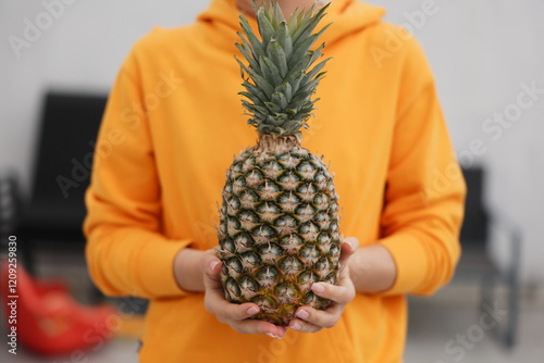 A vibrant and cheerful person holding a ripe pineapple, truly embodying freshness and a delightful tropical vibe photo