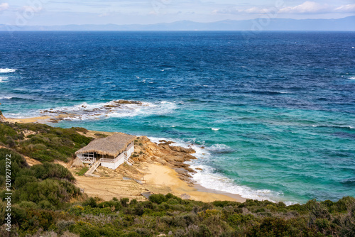 Beach house with straw roof near the sea with turquoise water photo