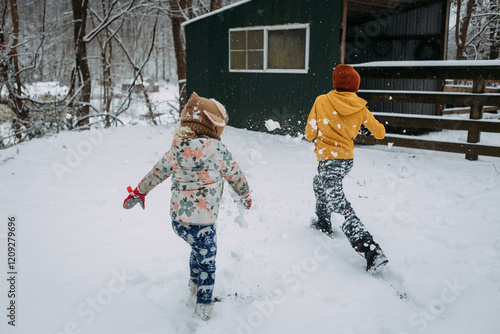 Sibling children having snowball fight in yard