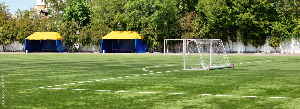 Vibrant soccer field ready for action under clear blue skies. Banner.
