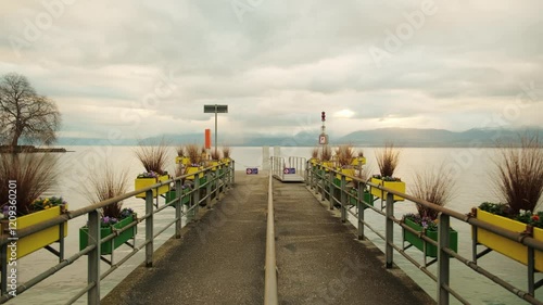Wide establishing shot of Rolle wharf at sunrise with Lake Geneva in Canton of Vaud Switzerland