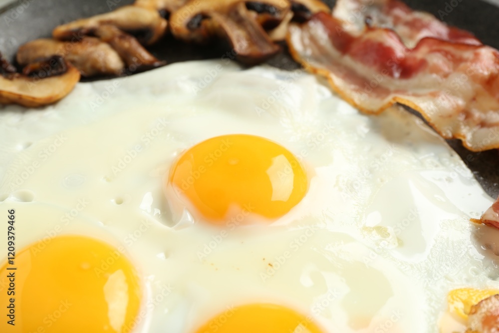 Tasty fried eggs with bacon and mushrooms in frying pan, closeup Tasty fried eggs with bacon and mushrooms in frying pan, closeup
