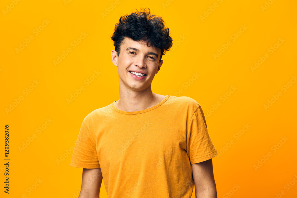 Young man smiling against a bright yellow background, wearing a casual orange t shirt, conveying a cheerful and positive mood, ideal for concepts of happiness and youthfulness Young man smiling against a bright yellow background, wearing a casual orange t shirt, conveying a cheerful and positive mood, ideal for concepts of happiness and youthfulness