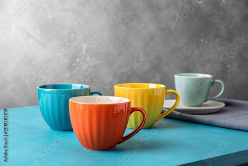 Three cups of different colors on a blue table on a gray background. High quality photo photo