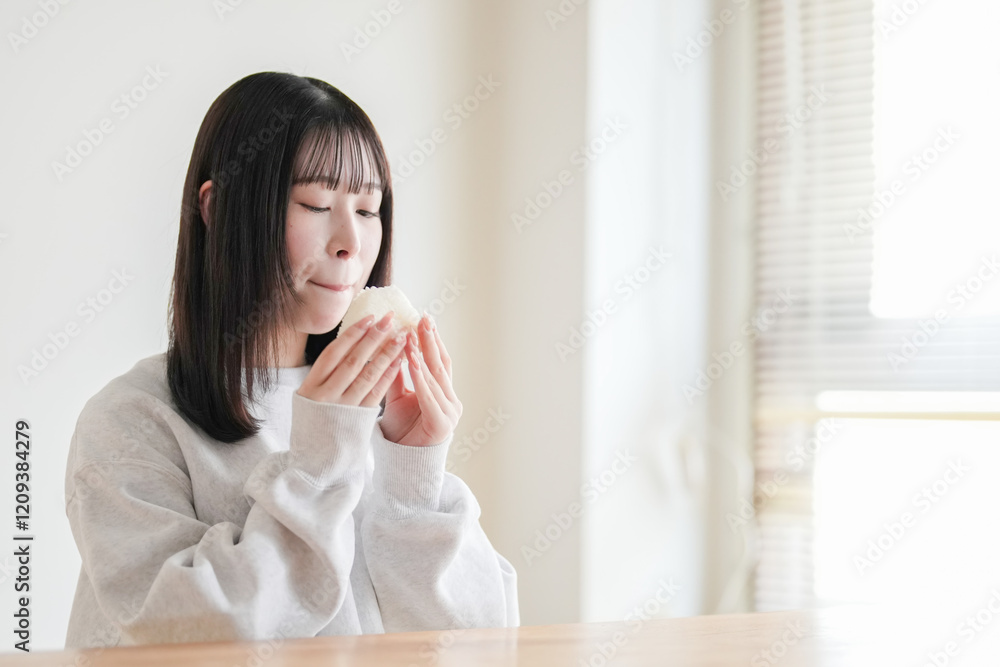 Young Japanese woman in her 20s sits in tatami room and enjoys rice ball made only of white rice. Young Japanese woman in her 20s sits in tatami room and enjoys rice ball made only of white rice.
