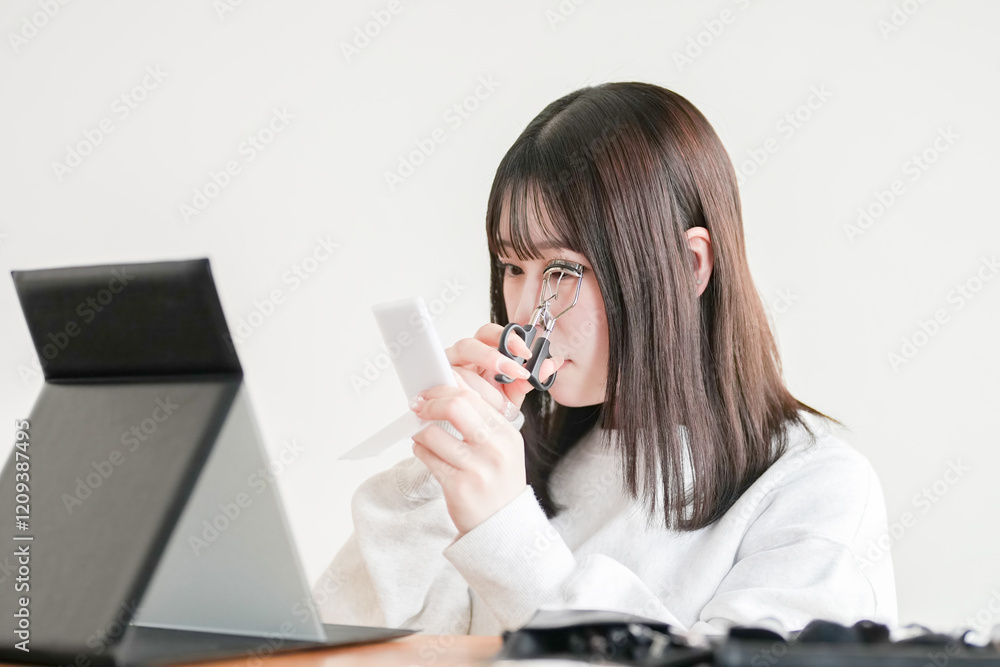A young Japanese woman in her 20s is sitting in a tatami room and applying makeup using professional makeup tools. A young Japanese woman in her 20s is sitting in a tatami room and applying makeup using professional makeup tools.