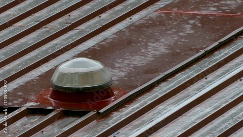 Torrential rain on the roof of a factory. 4K resolution.
View of the roof with a wet skylight and shiny from the reflection of the water, creating a visual pattern with contrast. photo