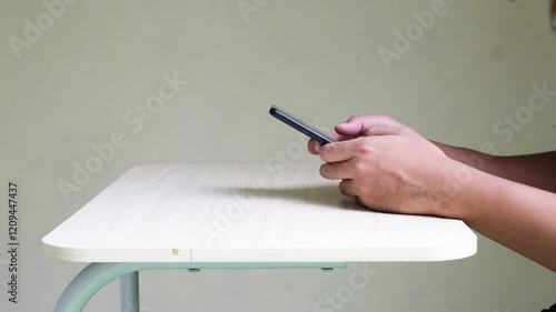 Side view of person hands typing on mobile phone above a table