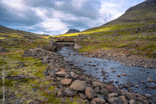 A striking landscape near Breiðdalsvík in East Iceland, featuring a winding watercourse surrounded by rugged rocks and majestic mountains photo