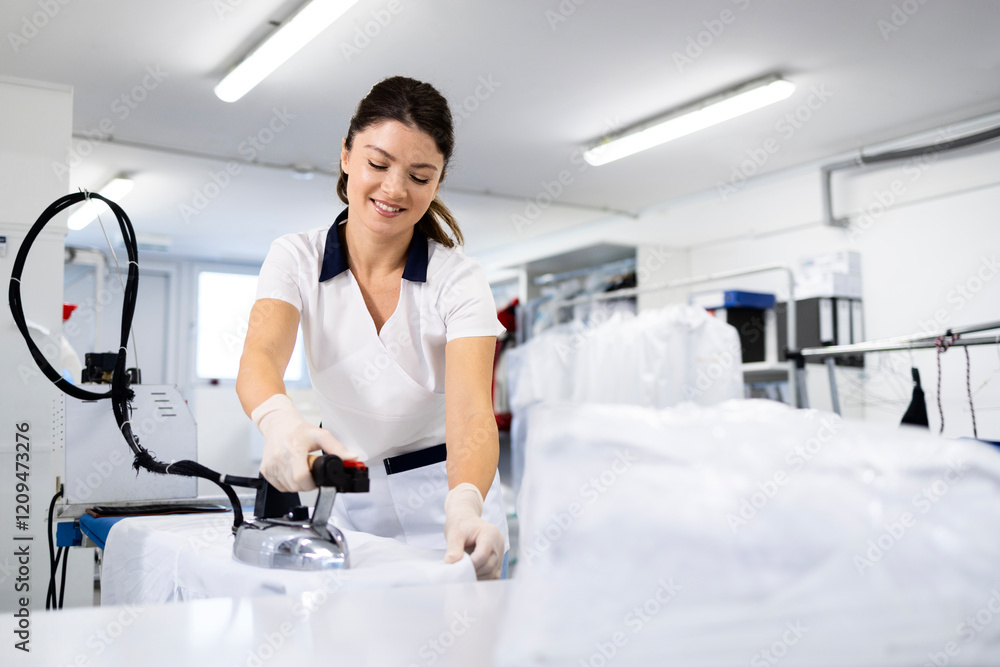 Fototapeta premium Professional dry cleaning worker ironing clean laundry for the customer.