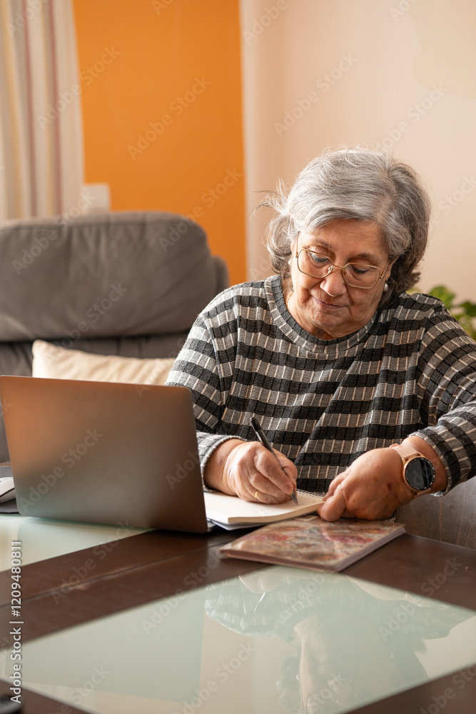 elderly woman working with a computer and her notepad elderly woman working with a computer and her notepad