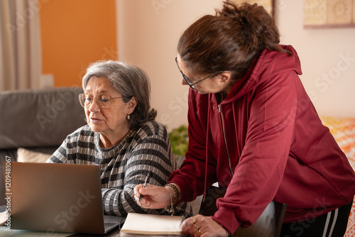 woman taking notes while her mother is at the computer