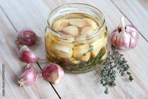 Garlic cloves pickled in sunflower oil and thyme. A glass jar full of garlic cloves should be kept in the refrigerator.