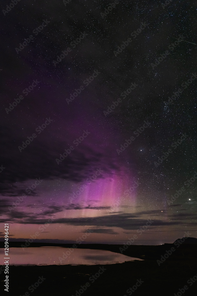 Fototapeta premium Aurora borealis over Snaefellsnes peninsula, West Iceland, vivid purple and pink hues, starry night sky, serene water reflection, breathtaking natural wonder
