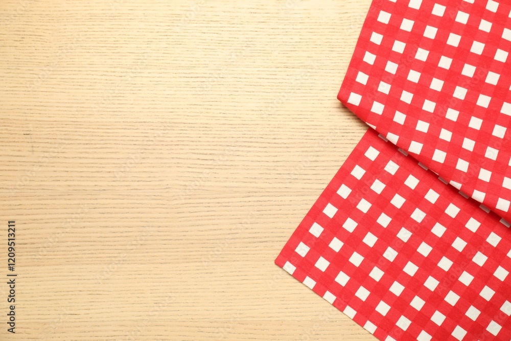 Obraz premium Red checkered tablecloth on wooden background, top view. Space for text