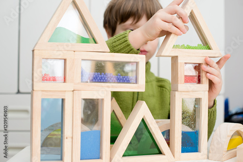 Boy plays with different shape and color sensory blocks filled with sand, water, beads and acrylic. Game for creativity, improving imagination, construction, creating buildings, houses, castles. 
