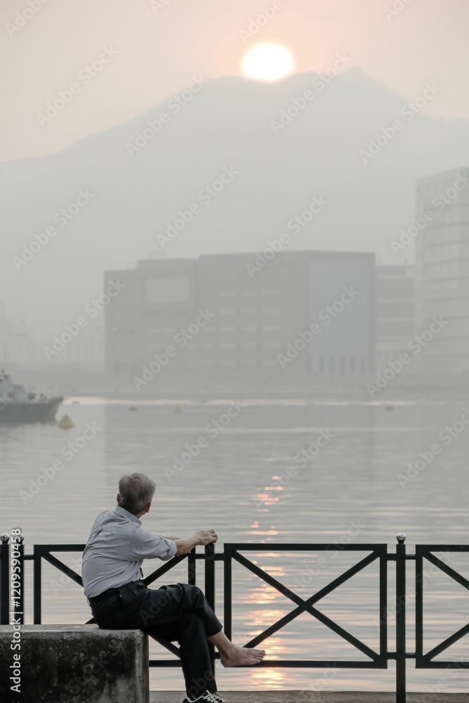 Elderly man by waterfront at sunrise