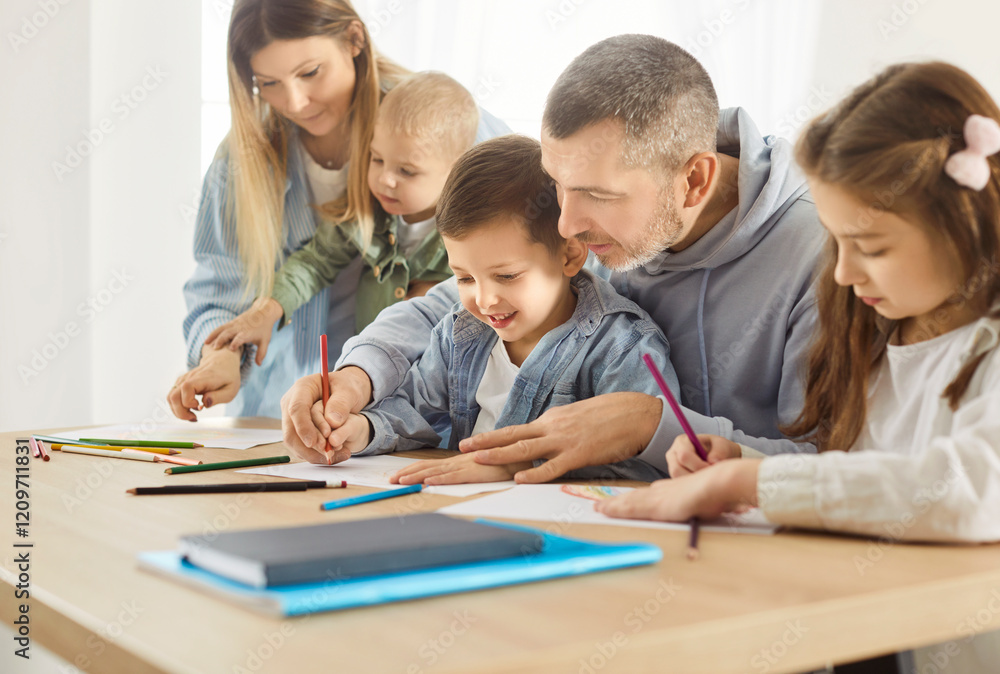 Portrait of a cheerful smiling parents sitting at table with their happy children and drawing on a white sheet of paper in the living room at home. Family leisure and education concept. Portrait of a cheerful smiling parents sitting at table with their happy children and drawing on a white sheet of paper in the living room at home. Family leisure and education concept.