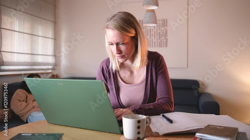 A mother works from home on her laptop in the living room, focused on her tasks, while her children play energetically in the background.