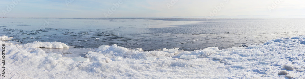 Panoramic view of freezing Baikal Lake on January day. Icy shore with ice floes on the beach during freeze-up. Lakeside landscape. Winter natural background. Changing seasons, environment Panoramic view of freezing Baikal Lake on January day. Icy shore with ice floes on the beach during freeze-up. Lakeside landscape. Winter natural background. Changing seasons, environment