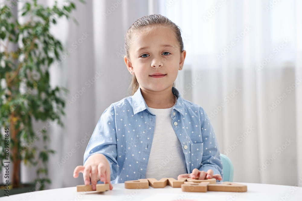 Little girl learning alphabet with wooden letters at white table indoors Little girl learning alphabet with wooden letters at white table indoors