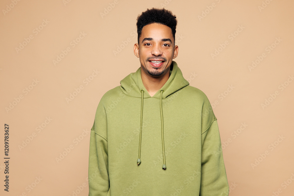 Young smiling happy cheerful man of African American ethnicity he wears green hoodie casual clothes looking camera isolated on plain pastel light beige background studio portrait. Lifestyle concept. Young smiling happy cheerful man of African American ethnicity he wears green hoodie casual clothes looking camera isolated on plain pastel light beige background studio portrait. Lifestyle concept.