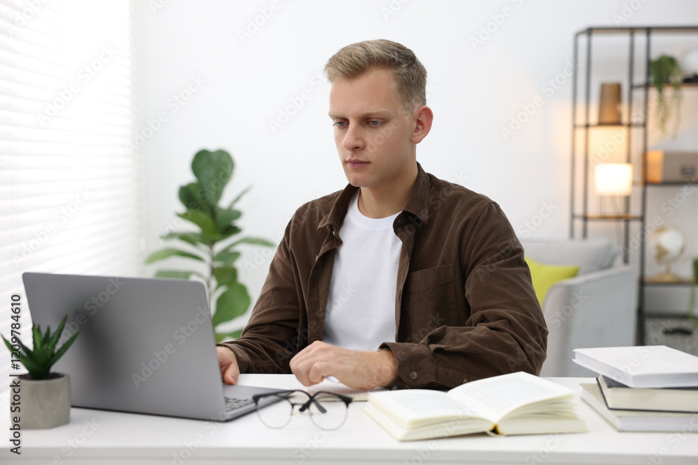 Student preparing for exam with laptop at table indoors Student preparing for exam with laptop at table indoors