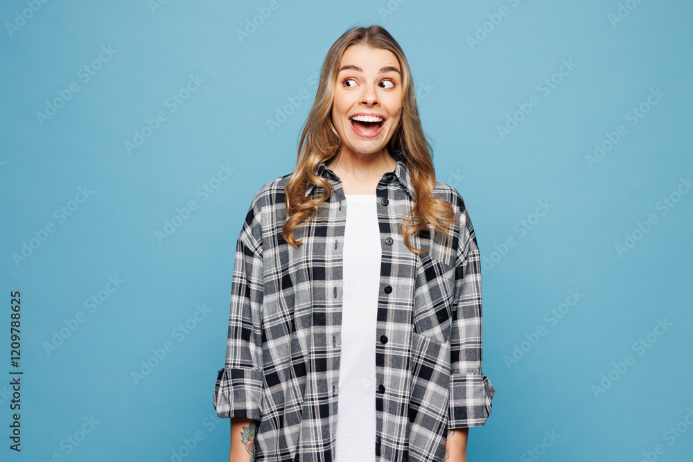 Young shocked surprised excited fun overjoyed woman she wears checkered shirt casual clothes look aside on area isolated on plain pastel light blue cyan background studio portrait. Lifestyle concept. Young shocked surprised excited fun overjoyed woman she wears checkered shirt casual clothes look aside on area isolated on plain pastel light blue cyan background studio portrait. Lifestyle concept.