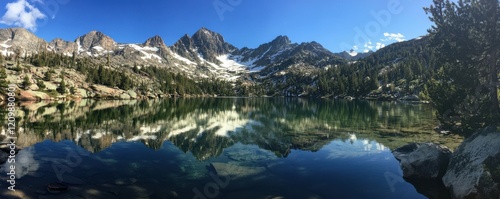 A serene mountain lake reflecting the snow-capped peaks that surround it, its waters crystal clear and inviting.
