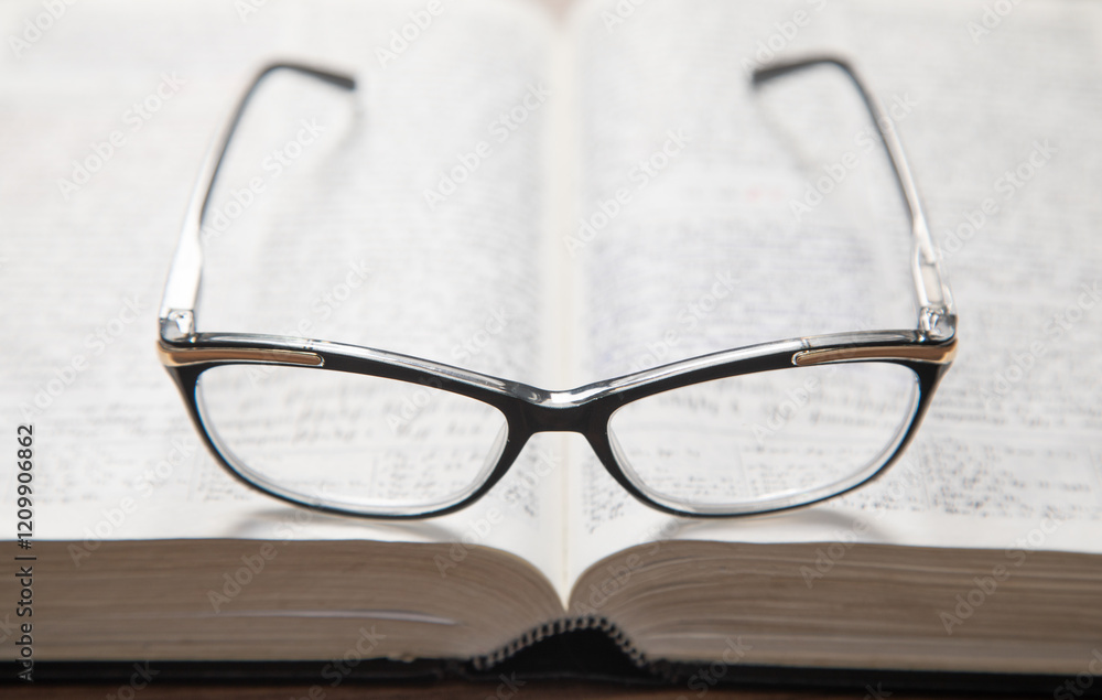 Eyeglasses and book on the wooden table.