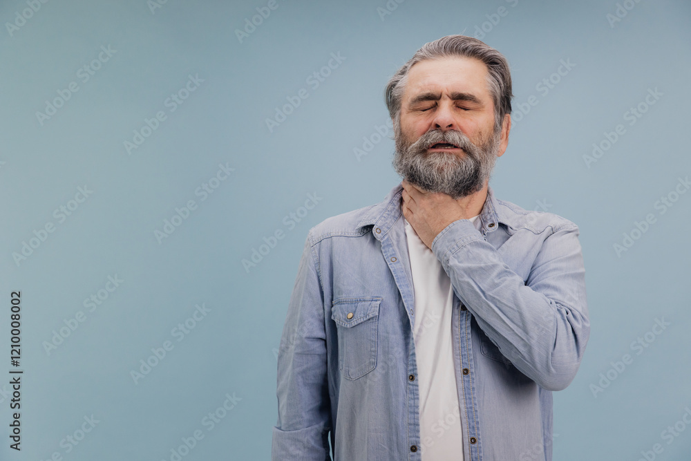 Senior man suffering from sore throat touching neck with hand on blue background Senior man suffering from sore throat touching neck with hand on blue background