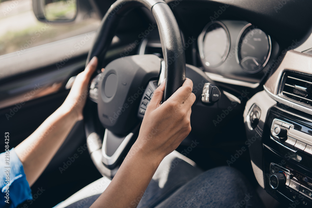 Naklejka premium Young woman confidently driving a modern car during a sunny day, capturing the essence of urban commuting and carefree travel