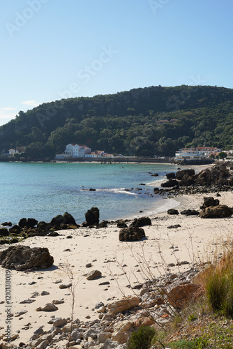 Beautiful beach with a blue ocean and mountains in the background. The beach is empty and the sky is clear Portinho da Arrábida beach, Setúbal, Portugal. photo