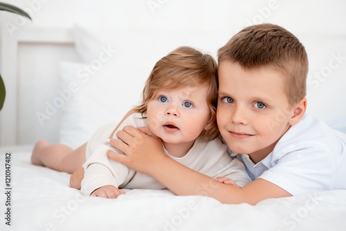 Obraz na plátne Two baby brothers hug and kiss on the bed at home, brotherly love and care, port