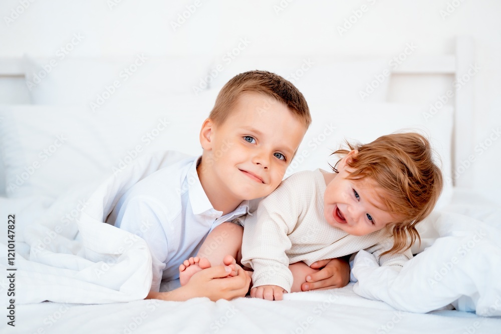 Brother hugs smiling younger brother, brotherly love and care, two children on the bed close-up Brother hugs smiling younger brother, brotherly love and care, two children on the bed close-up